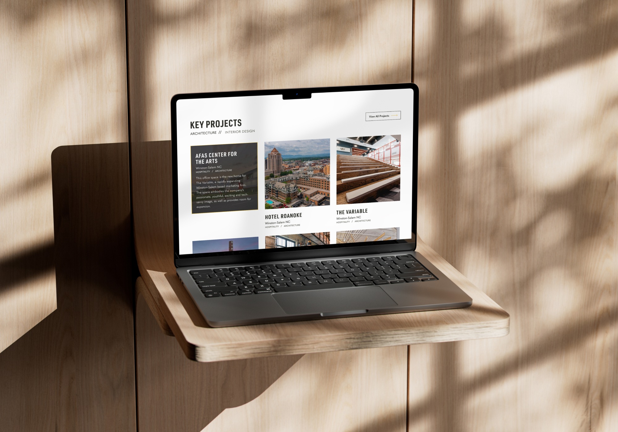 Laptop on shelf showcasing services animation page of website design for STITCH Design Studio.