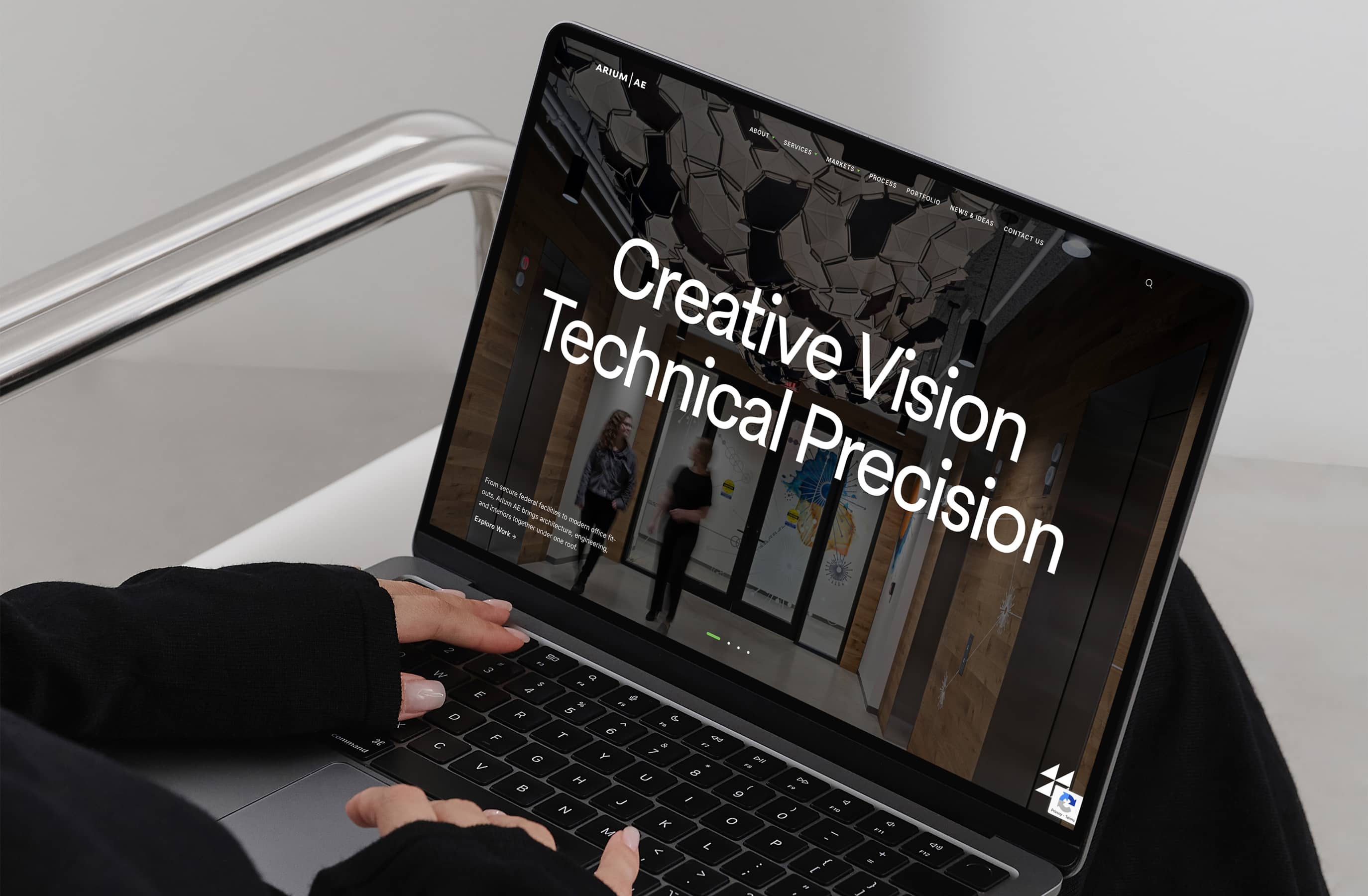 A person in a black sleeve uses a laptop displaying the text 