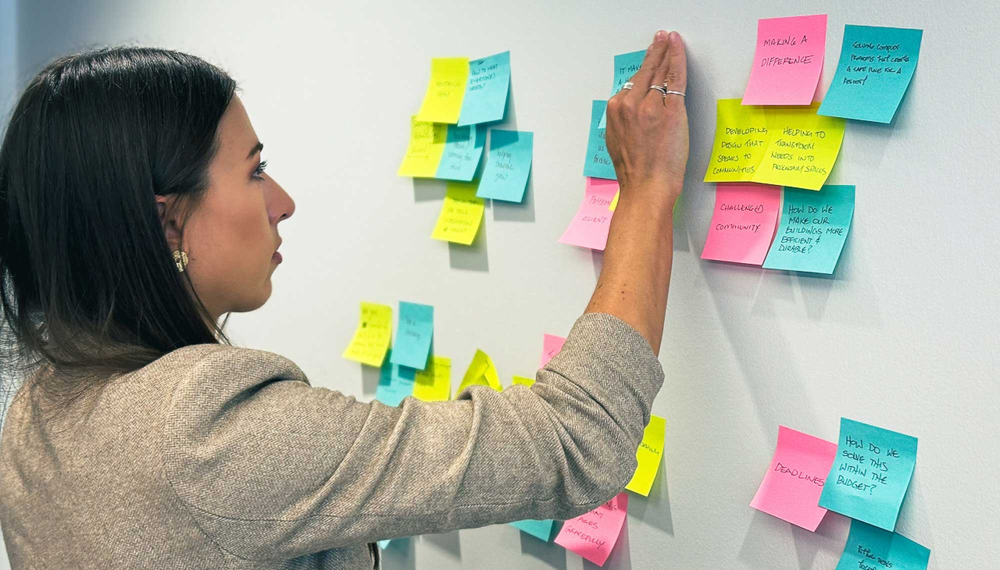 Sabrina Pfautz, Chief Creative Officer, arranges colorful sticky notes on a wall during an AEC brand planning workshop.