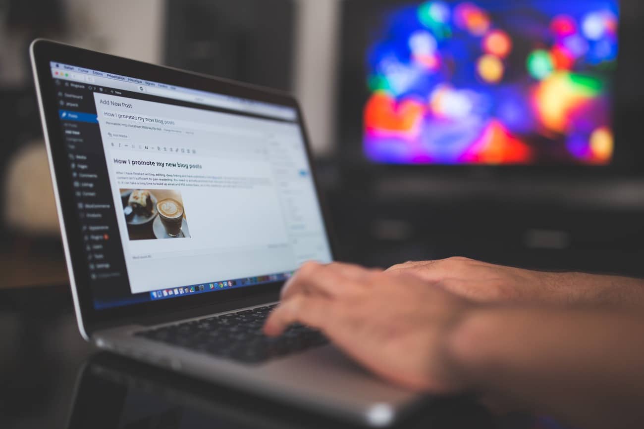Website maintenance project manager typing on a laptop while editing a new WordPress blog post